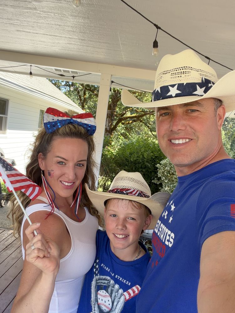 A woman, a boy and a man in patriotic hats smiling for a selfie on a porch